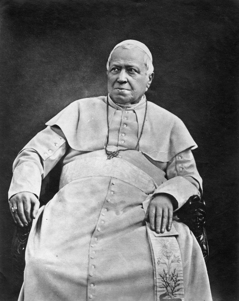 A photograph of Pope Pius IX in 1875, seated in white cassock and cape.