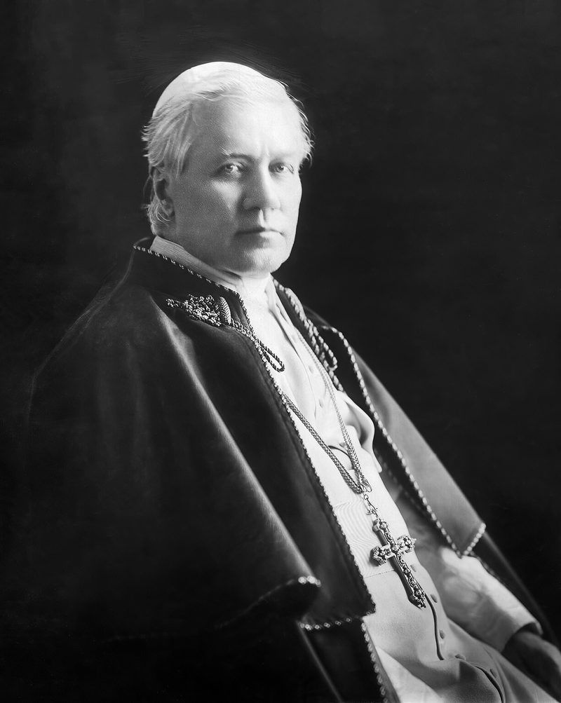 A photograph of Pope St Pius X, seated, in white cassock with a pectoral cross.