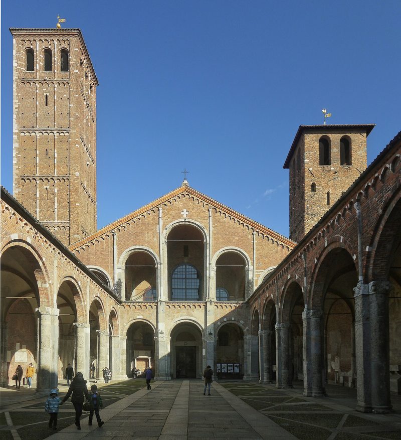 The atrium of the Basilica of Sant’Ambrogio in Milan: a Romanesque brick courtyard with arcades and two bell towers.