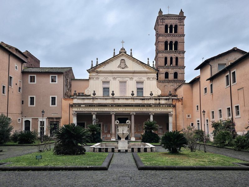 The façade and courtyard of Santa Cecilia in Trastevere, Rome, with a medieval bell tower.
