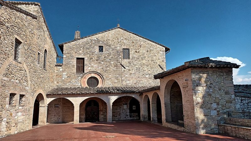 The small stone church and convent of San Damiano near Assisi, with a brick arcade and a little bell tower.
