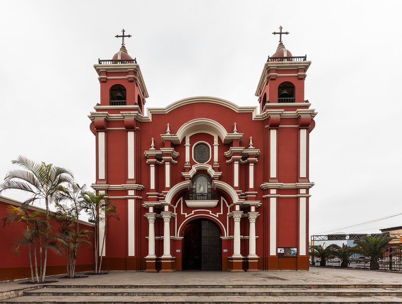 The Church of Santa Rosa in Lima, Peru: a red and white façade between two bell towers, with palm trees.