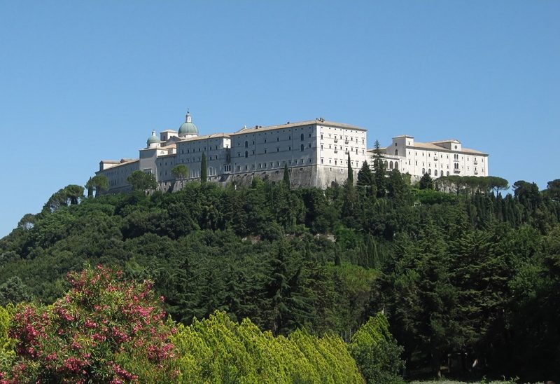 The Abbey of Monte Cassino seen from below, across a green valley.